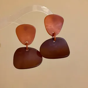 Close-up of retro irregular resin earrings with orange and brown dyed geometric pendants