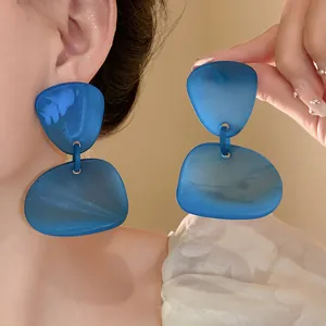 Detail view of blue irregular resin geometric drop earrings with silver needle post.
