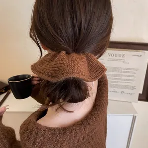 Close-up of a brown knitted scrunchie worn on a low hair bun in an autumn style