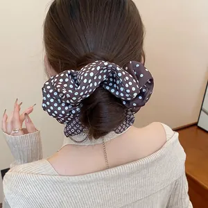 Oversized brown polka dot pleated scrunchie hair tie shown on a stylish bun hairstyle