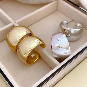 Close-up view of gold and silver C-shaped hoop earrings with hammered metal texture