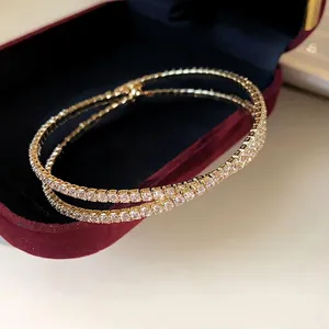 Elegant gold crisscross double-layered open bangle with sparkling white zircon stones.