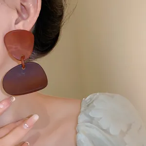 Detail view of irregular geometric drop earrings with mottled resin texture worn by model.
