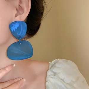 Detailed close-up showing blue irregular marble resin geometric drop earrings worn by a model
