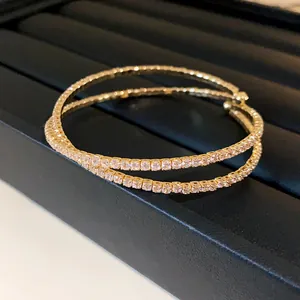 Macro view of a double-layered crisscross gold bangle featuring sparkling pavé zirconia stones.