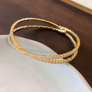 Detailed view of the double-layer crisscross gold bracelet with sparkling cubic zirconia stones.
