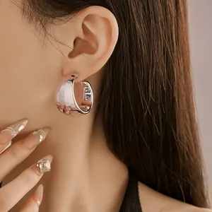 Close-up view of textured silver chunky C-shaped hoop earrings on a female model