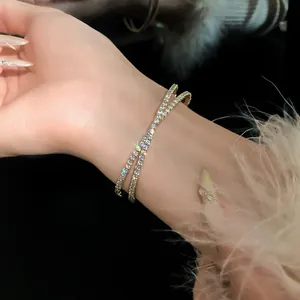 Detail showing an elegant gold-tone criss-cross bangle with sparkling cubic zirconia
