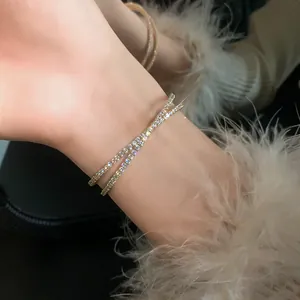 Close-up of sparkling double-layer crisscross zircon open bangle bracelet on wrist.