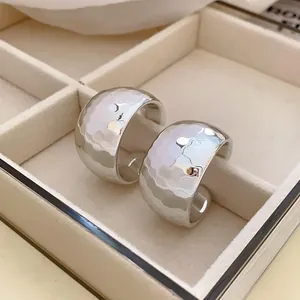 Detailed view of silver-toned hammered C-shaped hoop earrings inside a velvet jewelry tray