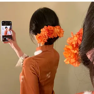 Back view of a woman wearing a vintage-style orange fabric flower hairpin in her hair