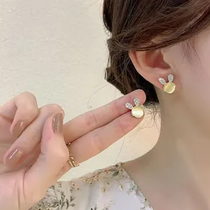 Detailed view of cat-eye stone rabbit earrings with sparkling crystal accents worn on ear