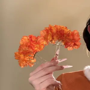 Detailed view of vintage-inspired orange fabric flower hairpins with elegant metal stems