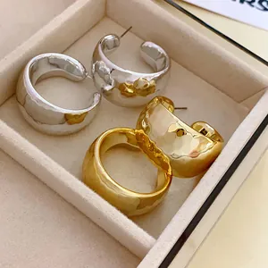 Close-up of hammered gold and silver C-shaped chunky hoop earrings in a jewelry tray.