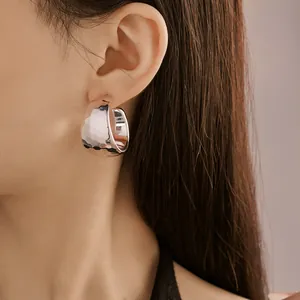 Close-up of minimalist silver-tone C-shaped hoop earrings with hammered texture on model ear