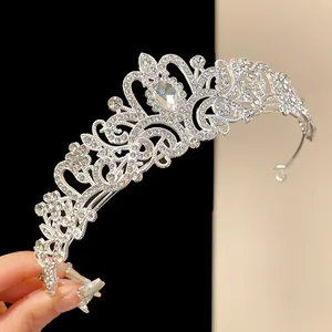Detail shot of a silver rhinestone tiara with floral patterns and a teardrop crystal centerpiece.