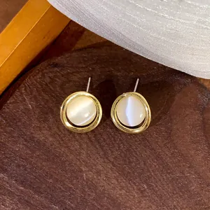 Close-up detail of vintage cat's eye stone stud earrings with gold circle frame