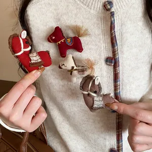 Vue détaillée de broches cheval tricotées à la main sur un cardigan blanc