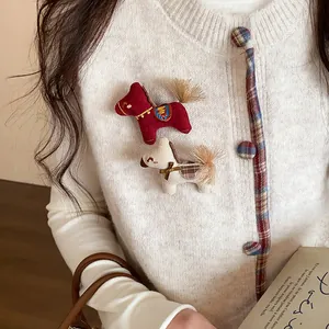 Détail de jolies broches poney tricotées avec des nœuds sur un cardigan blanc