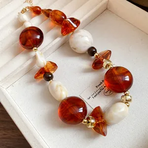 Close-up of irregular amber and marbled resin bead necklace in vintage Maillard style