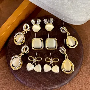 Detail view of vintage cat-eye stone earrings in gold finish with crystal accents.