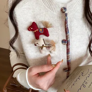 Gros plan de mignonnes broches en forme de poney tricoté sur un cardigan blanc élégant