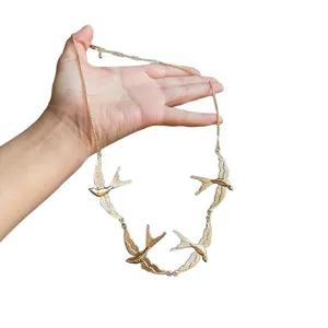 Elegant gold-tone metal swallow necklace with four bird pendants on a delicate chain