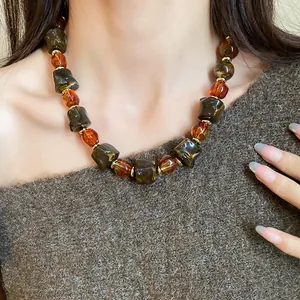 Detailed macro view of an irregular vintage Maillard-style necklace worn by a model