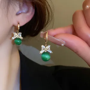 Close-up of elegant cat's eye stone hoop earrings with crystal bow design shown on model.