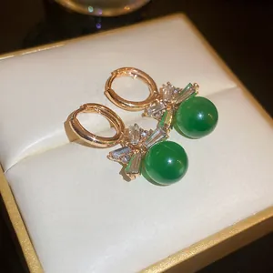 Close-up of retro green cat-eye hoop earrings with zircon accents on a gift box