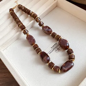Detail shot of a retro marbled brown bead necklace with gold accents in a jewelry tray