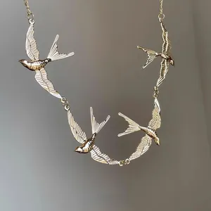 Detailed close-up of gold swallow pendants on a delicate necklace with flying bird design