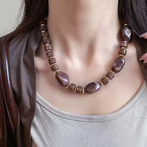 A close-up view of a vintage Maillard style marbled bead necklace worn by a model