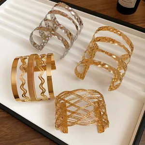 Vista dettagliata di bracciali rigidi aperti in metallo multistrato oro e argento esposti.