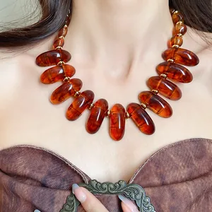 Close-up detail of retro Maillard style amber-colored translucent bead necklace on a model