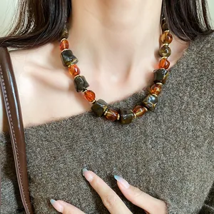 Detailed close-up of a retro irregular marbled bead necklace with warm amber tones.