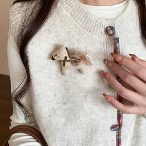 Vue détaillée d'une jolie broche cheval en tricot crème sur un cardigan en blanc