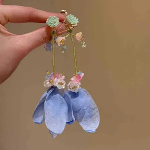 Close-up of elegant fabric flower tassel earrings with blue petals and bead details