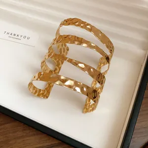 Dettaglio del bracciale a polsino dorato a più strati con finitura martellata e pieghettata