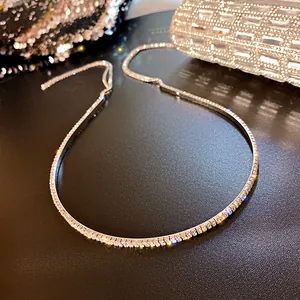 Détail d'un long serre-tête argenté avec des strass étincelants sur un fond noir texturé.
