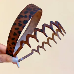 Detailed close-up showing leopard print matte headband and brown zigzag wave hair hoop set