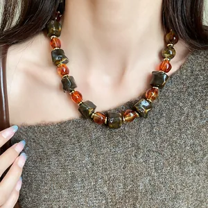 Close-up of Maillard retro necklace with irregular marbled amber beads on a model.