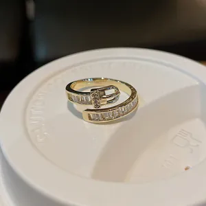 Close-up detail of a gold-plated belt buckle ring set with sparkling zircons
