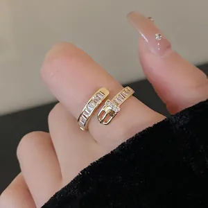 Close-up detail of a gold-plated belt buckle ring adorned with sparkling baguette zircons