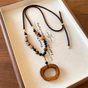 Detailed view of bohemian ethnic necklace featuring wood beads and amber resin pendant