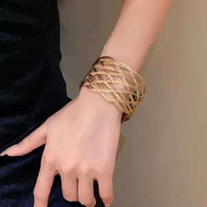 Elegante bracciale rigido in metallo intrecciato multistrato dorato indossato dal modello.