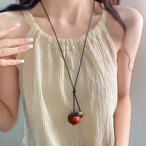 Detail of a retro bohemian ceramic persimmon pendant necklace worn by a model