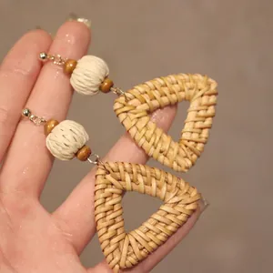 Vue macro détaillée de boucles d'oreilles pendantes en raphia tressé avec perles.