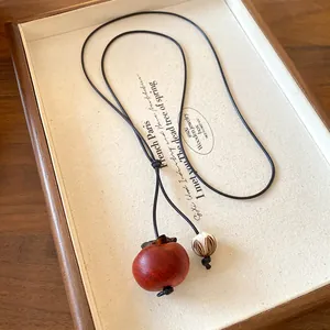 Close-up of bohemian ceramic necklace with persimmon-shaped pendant and patterned bead