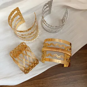 Dettaglio di bracciali a polsino in metallo oro e argento con texture martellata